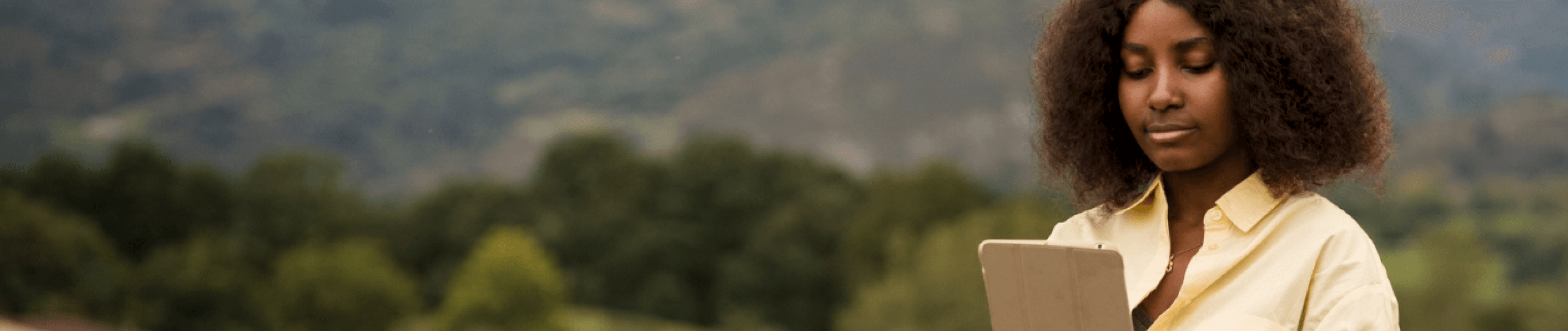 woman siting in what looks like a field with a tab.png